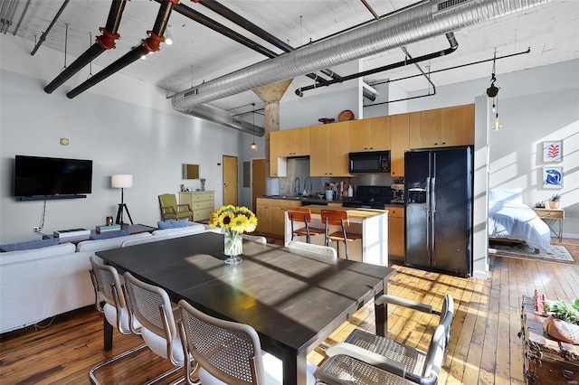 dining space with hardwood / wood-style flooring and a towering ceiling