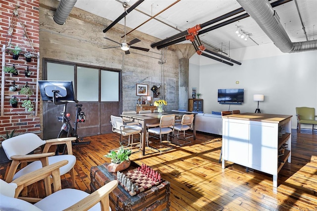 living room with wood-type flooring, a ceiling fan, and a high ceiling