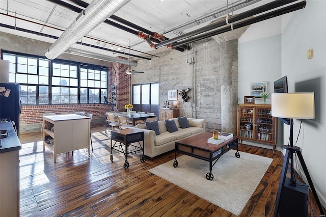 living area featuring a high ceiling, hardwood / wood-style floors, and brick wall