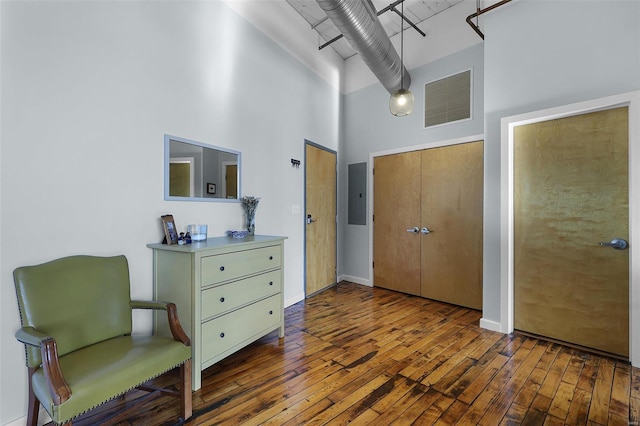 entryway featuring a high ceiling, wood-type flooring, electric panel, and baseboards