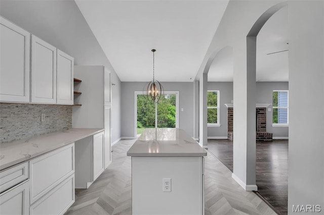 283 Sonnet Cir, Wentzville, MO 63385 - kitchen with baseboards, a kitchen island, arched walkways, tasteful backsplash, and white cabinets