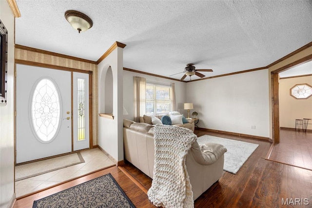 foyer featuring ornamental molding, hardwood / wood-style flooring, ceiling fan, baseboards, and a textured ceiling