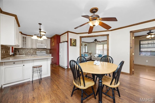 dining space featuring dark wood finished floors, a ceiling fan, baseboards, and ornamental molding