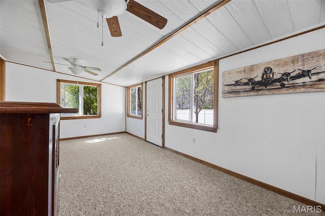 empty room with ceiling fan, carpet flooring, vaulted ceiling, and baseboards