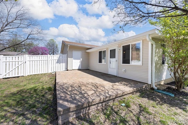 rear view of house featuring fence, a gate, and a patio area