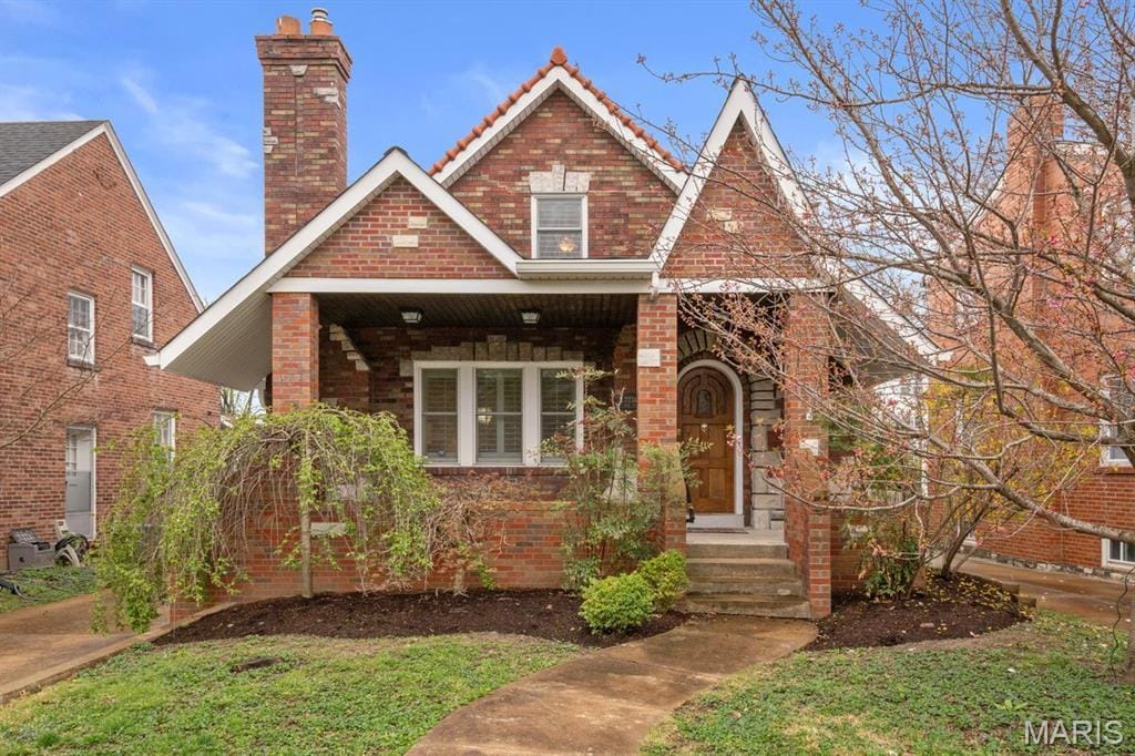 7734 Wise Ave, Saint Louis, MO 63117 - tudor house with a chimney, a tile roof, and brick siding