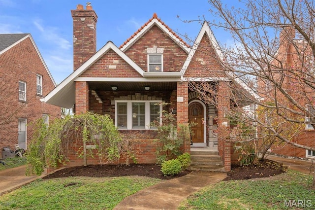 7734 Wise Ave, Saint Louis, MO 63117 - tudor house with a chimney, a tile roof, and brick siding