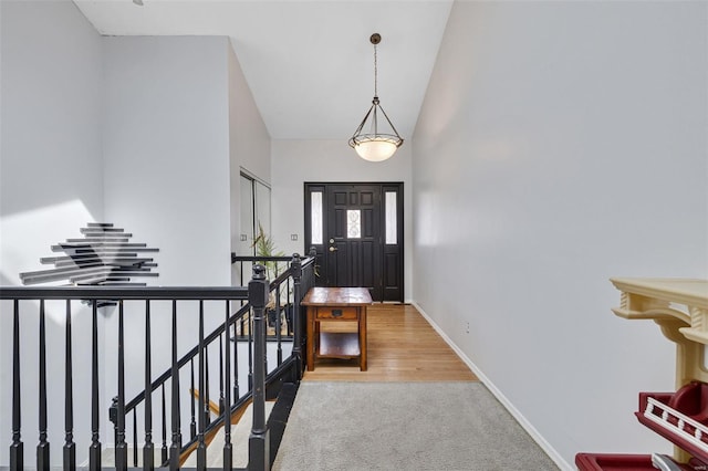 carpeted entrance foyer with baseboards and a towering ceiling