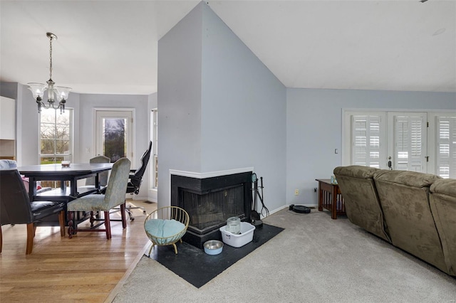 living room with a chandelier, baseboards, a multi sided fireplace, lofted ceiling, and light wood-type flooring