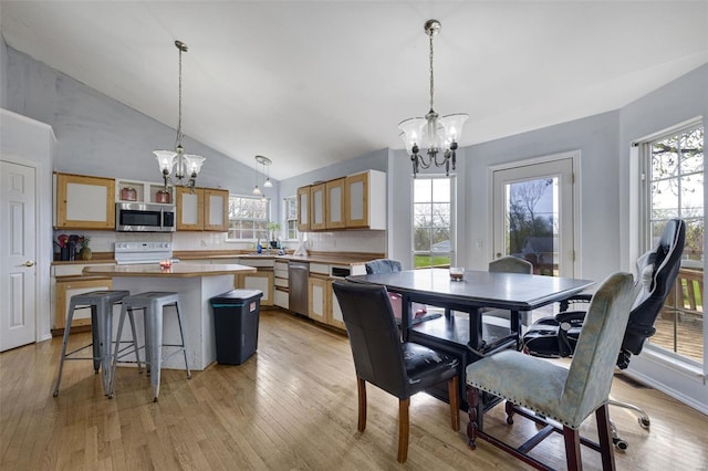 dining area with a chandelier, plenty of natural light, light wood-type flooring, and high vaulted ceiling