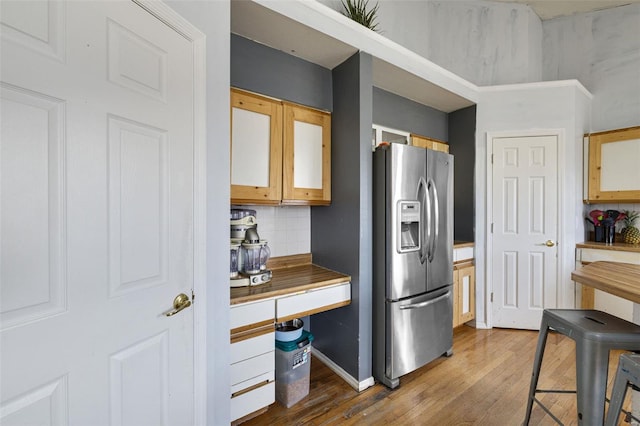 kitchen featuring stainless steel fridge, wood finished floors, backsplash, and baseboards