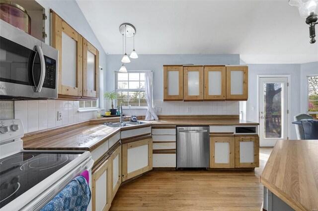 kitchen featuring stainless steel appliances, a sink, lofted ceiling, light wood-type flooring, and healthy amount of natural light