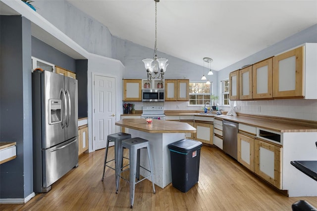 kitchen featuring appliances with stainless steel finishes, a chandelier, tasteful backsplash, vaulted ceiling, and light wood-style flooring