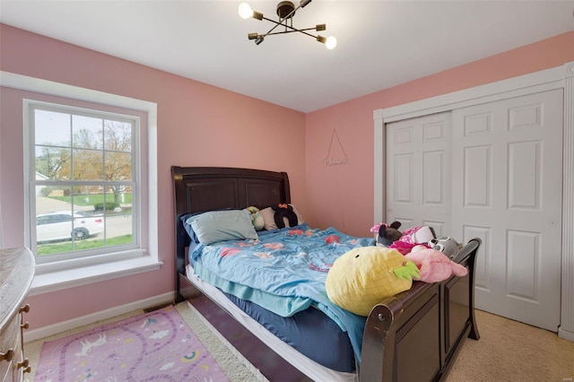 bedroom featuring a chandelier, a closet, light colored carpet, and baseboards