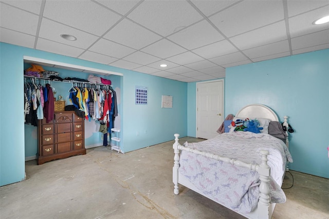 bedroom featuring a drop ceiling, unfinished concrete floors, a closet, and recessed lighting