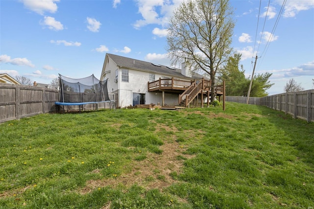 back of property with a trampoline, a wooden deck, stairs, and a chimney