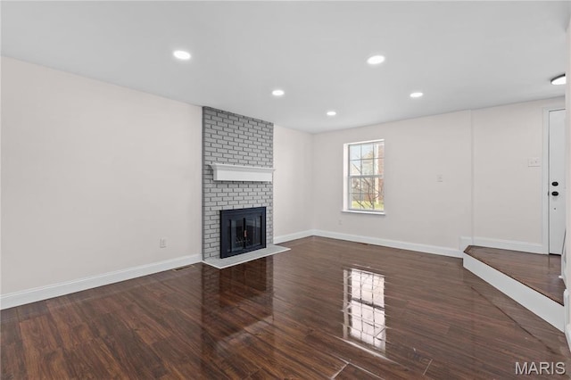 unfurnished living room with wood finished floors, a fireplace, baseboards, and recessed lighting