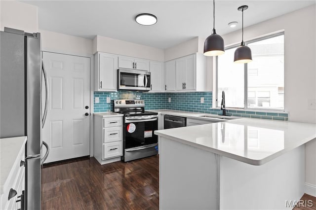 kitchen with appliances with stainless steel finishes, a sink, a peninsula, and light countertops