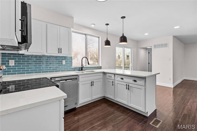 kitchen with a sink, stainless steel appliances, a peninsula, light countertops, and tasteful backsplash