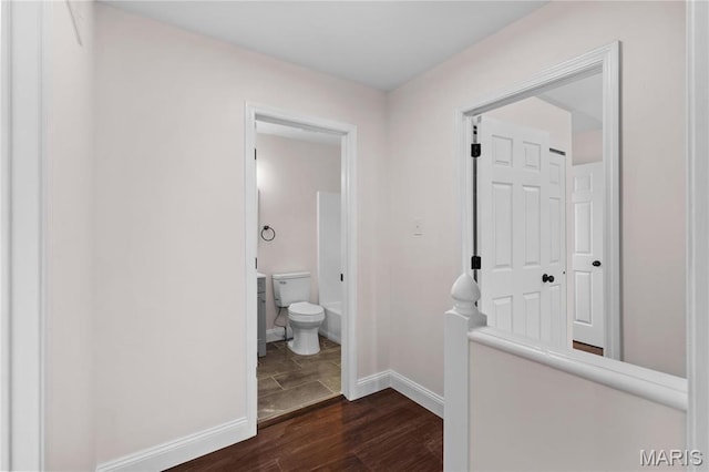 bathroom with toilet, wood finished floors, and baseboards