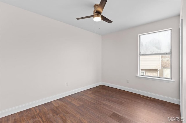 unfurnished room featuring baseboards, dark wood finished floors, and a ceiling fan