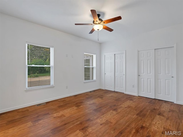602 S Ballas Rd, Saint Louis, MO 63122 - unfurnished bedroom with multiple windows, multiple closets, wood finished floors, and ceiling fan