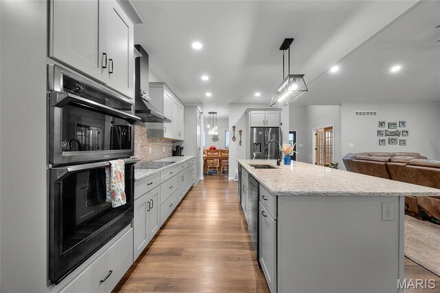 13160 Mammoth Rd, De Soto, MO 63020 - kitchen with black appliances, a kitchen island with sink, light wood-style floors, pendant lighting, and backsplash