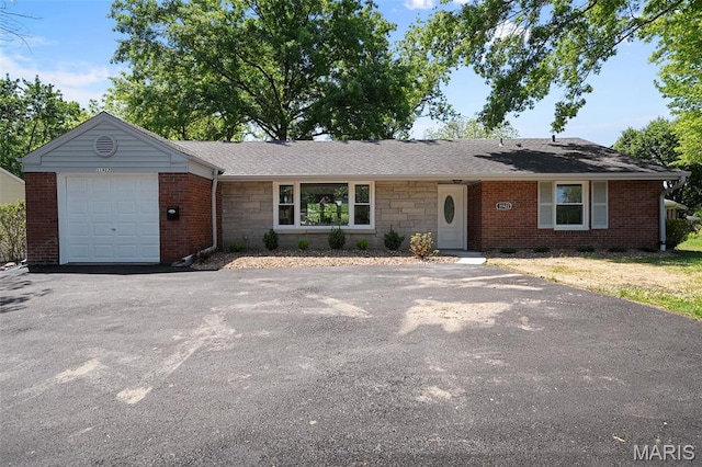 single story home with asphalt driveway, a garage, and brick siding