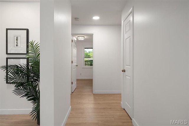 corridor featuring baseboards, light wood finished floors, and recessed lighting