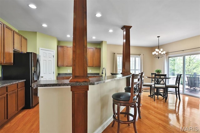 1304 Forest Way, Wentzville, MO 63385 - kitchen with ornate columns, fridge with ice dispenser, light wood finished floors, a kitchen breakfast bar, and recessed lighting
