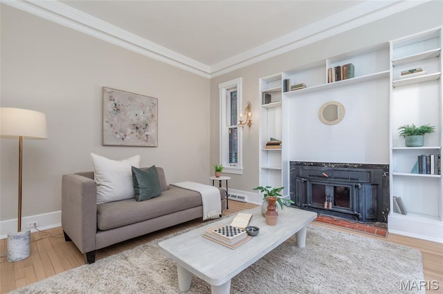 44 Kingsbury Pl, Saint Louis, MO 63112 - living room featuring wood finished floors, a glass covered fireplace, ornamental molding, built in features, and baseboards