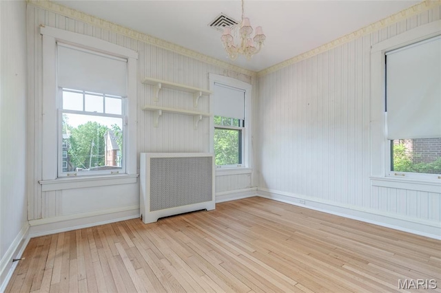 44 Kingsbury Pl, Saint Louis, MO 63112 - unfurnished living room with wood-type flooring, a chandelier, baseboards, and radiator heating unit