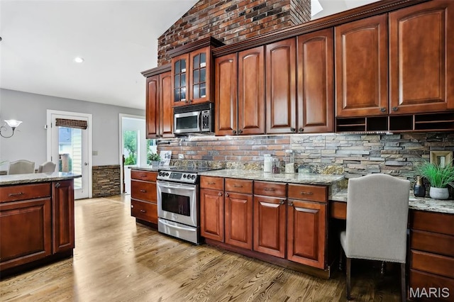 2113 Fairway Bnd, Chesterfield, MO 63017 - kitchen with stainless steel appliances, light wood-style floors, light stone countertops, backsplash, and glass insert cabinets
