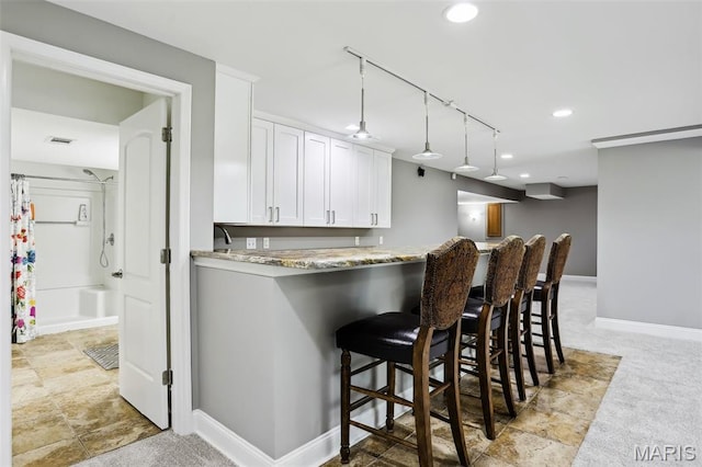 2113 Fairway Bnd, Chesterfield, MO 63017 - kitchen featuring white cabinetry, light stone countertops, baseboards, a breakfast bar area, and decorative light fixtures