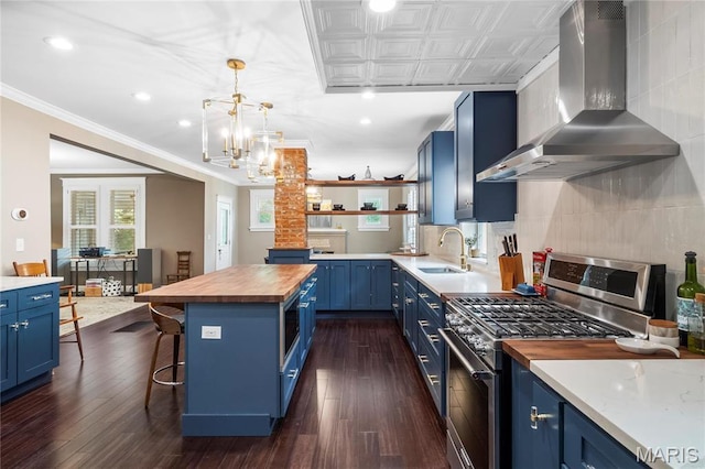 2521 High School Dr, Saint Louis, MO 63144 - kitchen with blue cabinets, butcher block counters, stainless steel gas range oven, wall chimney range hood, and open shelves