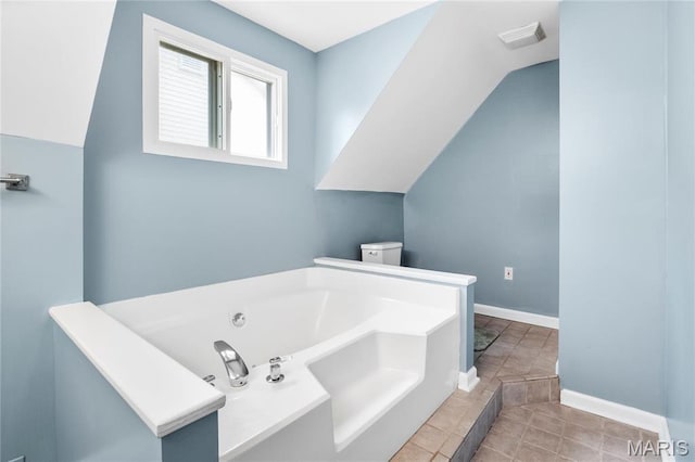 2521 High School Dr, Saint Louis, MO 63144 - bathroom with a garden tub, lofted ceiling, baseboards, and toilet