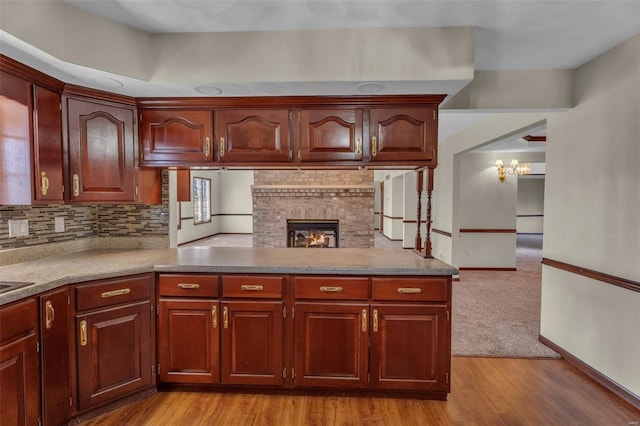 8620 State Route 163, Belleville, IL 62223 - kitchen with a brick fireplace, tasteful backsplash, light countertops, light wood-type flooring, and a peninsula