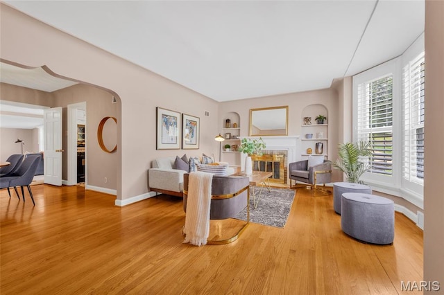 1010 Briarton Dr, Saint Louis, MO 63126 - living area featuring wood finished floors, built in features, a tiled fireplace, and arched walkways
