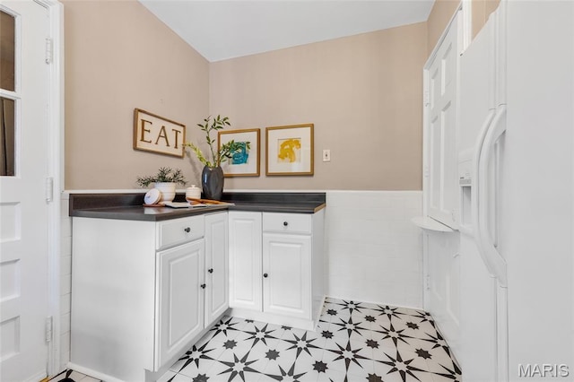 1010 Briarton Dr, Saint Louis, MO 63126 - kitchen featuring white fridge with ice dispenser, wainscoting, dark countertops, white cabinets, and light flooring