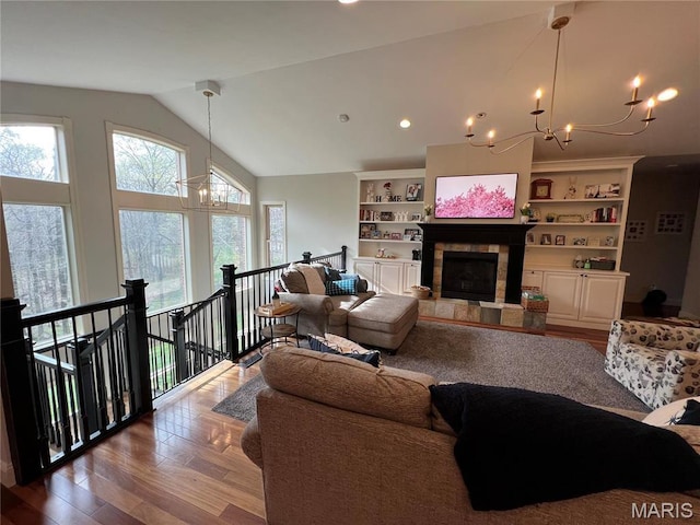 living room with a chandelier, lofted ceiling, wood finished floors, and a tile fireplace