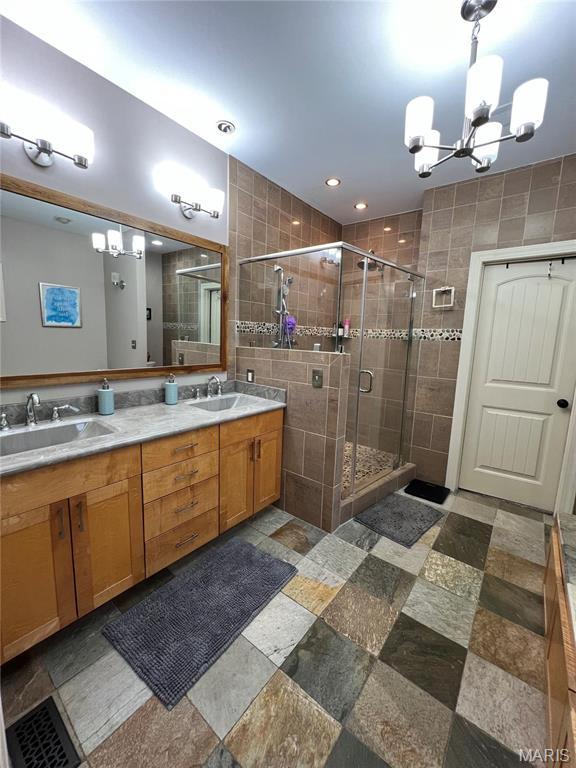 full bathroom with a chandelier, a stall shower, double vanity, and recessed lighting