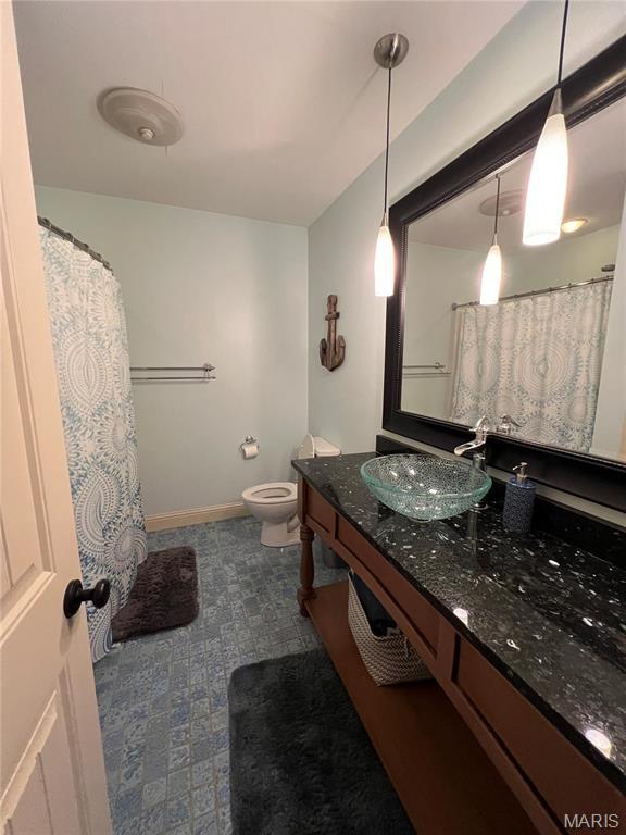 full bath with toilet, vanity, baseboards, and tile patterned floors