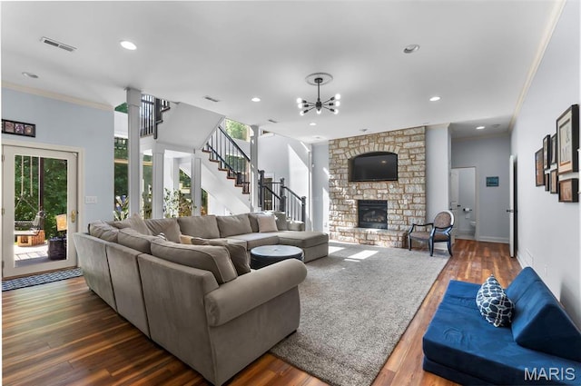 living room featuring a chandelier, healthy amount of natural light, a fireplace, crown molding, and dark wood-style floors
