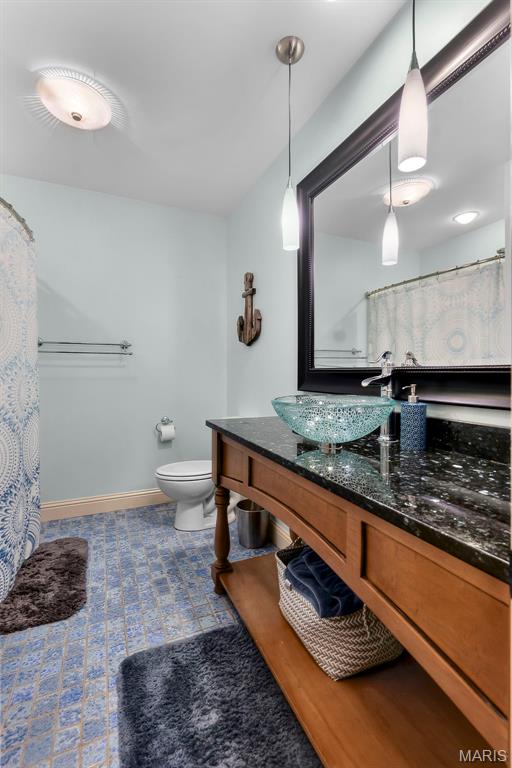 bathroom featuring toilet, vanity, and baseboards