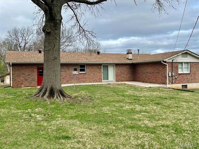 rear view of property with brick siding and a yard