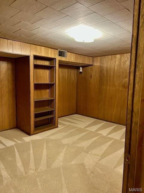 finished below grade area with wooden walls and light carpet