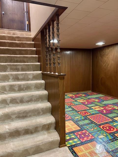 stairway featuring wooden walls