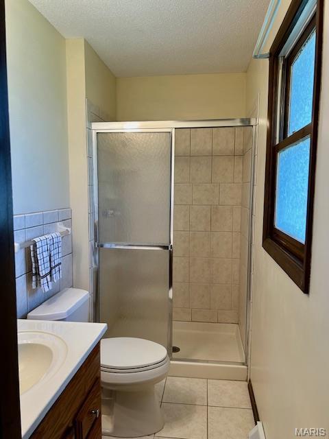 bathroom featuring tile patterned floors, a stall shower, vanity, toilet, and a textured ceiling