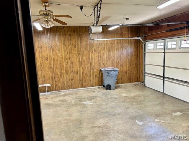 garage featuring wooden walls, a garage door opener, and ceiling fan