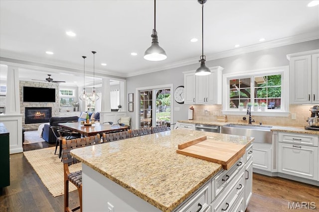 17 Denver Pl, Saint Louis, MO 63119 - kitchen featuring a stone fireplace, backsplash, white cabinets, a center island, and pendant lighting